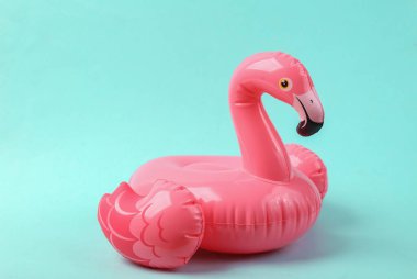 Mavi arka planda pembe şişme flamingo.