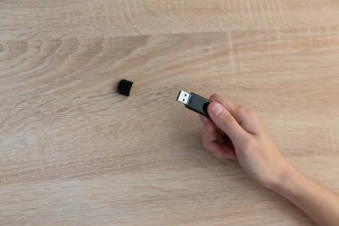 Tahta bir masada USB flaş bellek tutuyor.