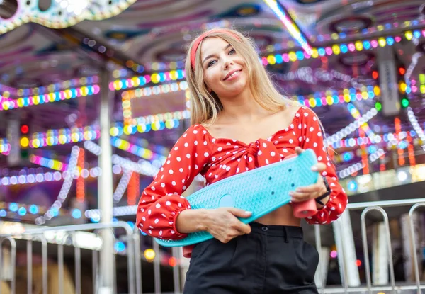 Şirin, neşeli, kuruşlu sarışın kadın lunaparkta eğleniyor.