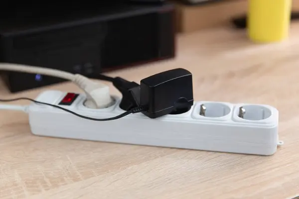 Extension cord with sockets, plugs and an adapter on the computer desk