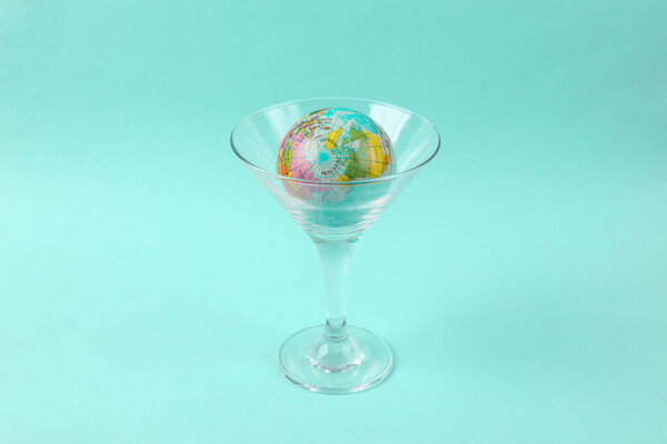Globe in cocktail glass on blue background. Fresh idea. Minimal party concept, creative layout