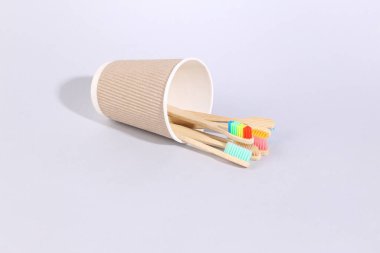 Gri arkaplanda karton bardakta tahta diş fırçaları.