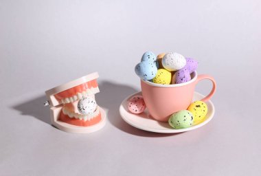 Renkli Paskalya yumurtaları ve gri arka planda çenesi olan fincan