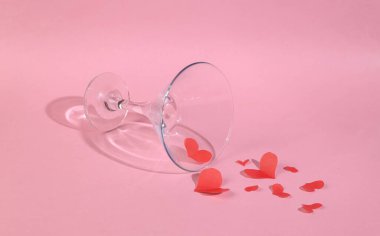 Pembe arka planda kırmızı kalpli kokteyl bardağı. Sevgililer günü partisi, 14 Şubat