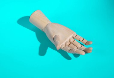 Uzun gölgeli bir turkuaz arka planda tahta el. En küçük yerleşim