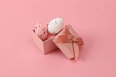 Paskalya yumurtaları pembe arka planda hediye kutusunda.