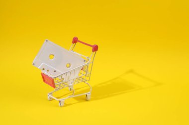 Sarı parlak arka planda ses kaseti olan mini alışveriş arabası.