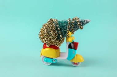 Turkuaz arka planda Noel ağacı olan mini scooter.