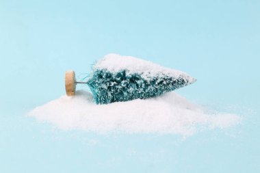 Mavi zemine kar serpiştirilmiş bir kar yığınındaki Noel ağacı. Noel konsepti