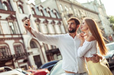 Genç aşık çift şehirde akıllı telefondan selfie çekiyor. Romantik aşk konsepti