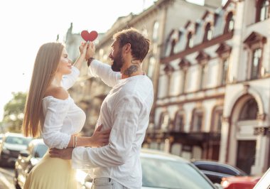 Aşık genç bir çift, ellerinde kırmızı bir kalple şehirde aşklarını gösteriyorlar.