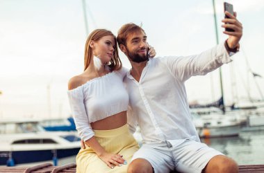 Birbirine aşık güzel bir çift yat kulübünde telefonda selfie çekiyor.