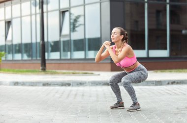 Formda bir kadın dışarıda çömeliyor. Aktif yaşam tarzı. Çömelme pratiği.