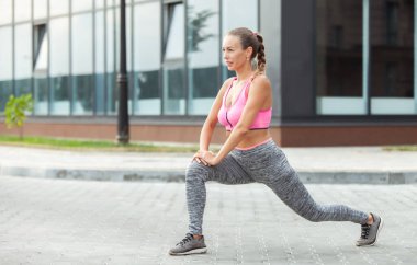 Formda bir kadın dışarıda bacak çalıştırıyor. Aktif yaşam tarzı. Esneme alıştırması yapıyorum.