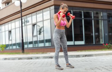 Aktif yaşam tarzı konsepti. Spor giyim bölümünde formda bir kadın, elinde dambıllarla kasları çalıştırıyor.