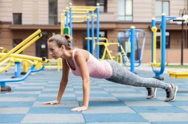 Active lifestyle. Fit woman push ups on outdoor workout playground
