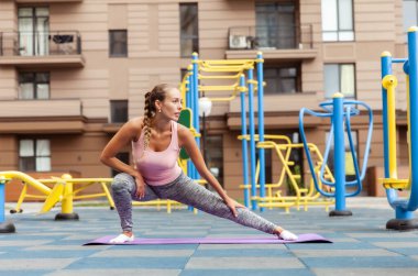 Açık alanda bacak esneme egzersizi yapan formda bir kadın. Etkin yaşam biçimi