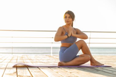 Kumsalda yoga yapan güzel, zinde bir kadın.