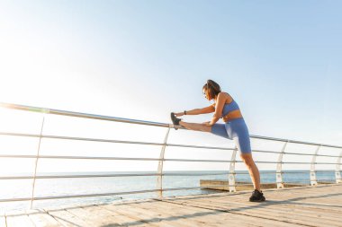 Sahilde bacak esneme egzersizi yapan fit bir kadın. Etkin yaşam biçimi