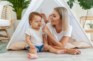 Genç anne ve küçük kızı evdeki bir çadırda birlikte vakit geçiriyorlar.