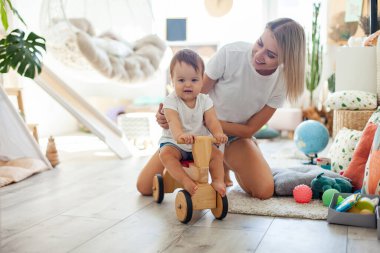 Anne ve küçük kızı oyun odasında vakit geçiriyorlar. Tahta scooterlı küçük bir kız. Anne bakımı, aşk konsepti