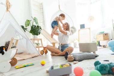 Küçük kızıyla birlikte sevimli bir anne oyun odasında oyuncaklarla oynuyor. Anne bakımı ve sevgi