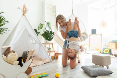 Küçük kızıyla birlikte sevimli genç bir anne oyun odasında oynuyor. Anne bakımı ve sevgi