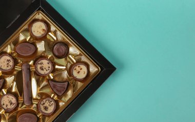 Açık mavi arka planda altın kaplamalı bir kutu çikolata. Üst Manzara. Boşluğu kopyala