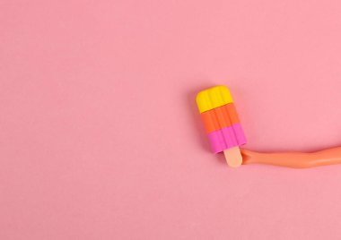 Bebeğin eli pembe arka planda dondurmayı tutuyor. Minimum konsept. Yaratıcı yerleşim