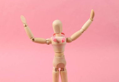 Pembe arka planda kulaklıkları olan tahta bir kukla. Müzik aşığı