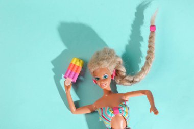 ODESSA, UKRAINE - 1 Kasım 2021: Mavi zemin üzerinde donmuş meyve suyu olan Barbie bebek. Asgari yaz konsepti