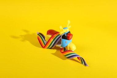 Sarı arkaplanda gökkuşağı sembolü olan oyuncak scooter.