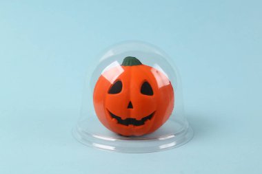 Mavi arka planda şeffaf kubbenin altında Cadılar Bayramı balkabağı Jack. Koruma, izolasyon kavramı. En küçük yerleşim