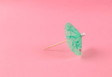 Pembe arka planda kokteyl şemsiyesi. En küçük yerleşim