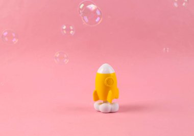 Pembe arka planda sabun köpükleri olan eğlenceli uzay roketi modeli. Rüya konsepti. Uzay uçuşları. En küçük yerleşim