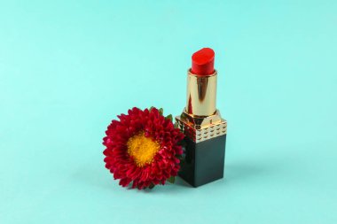 Kırmızı ruj, mavi arka planda kırmızı çiçek.