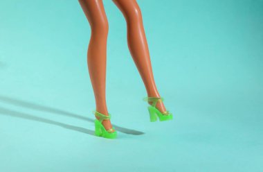 Mavi arka planda sandalet giymiş oyuncak bebek bacakları. Asgari moda düzeni