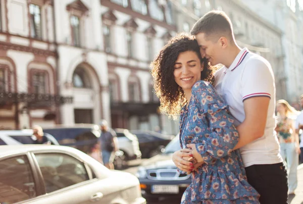 Şefkatli adam şehirde genç kadınına nazikçe sarılıyor. Aşık çift, ilişki konsepti 