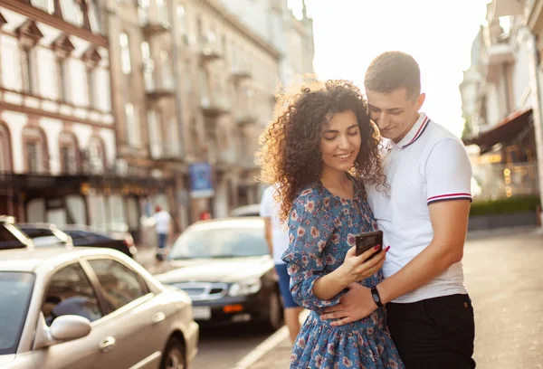 Genç çift şehirdeki akıllı telefon ekranına bakıyor, birlikte vakit geçiriyorlar, seyahat konsepti uyguluyorlar.