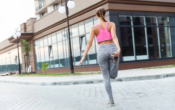 Formda bir kadın dışarıda bacak esnetiyor. Etkin yaşam biçimi