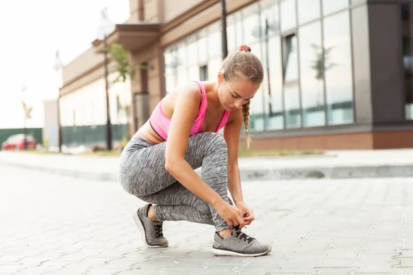 Açık havada ayakkabı bağcıklarını bağlayan formda bir kadın. Aktif yaşam tarzı. Sabah koşusu
