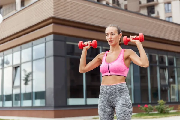 Aktif yaşam tarzı konsepti. Spor giyim bölümünde formda bir kadın, elinde dambıllarla kasları çalıştırıyor.
