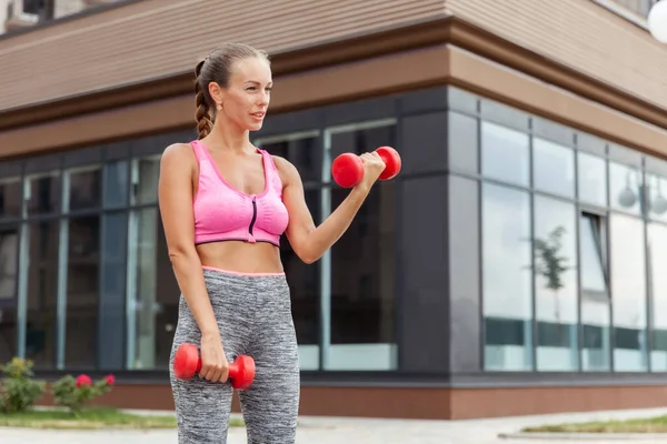 Aktif yaşam tarzı konsepti. Spor giyim bölümünde formda bir kadın, elinde dambıllarla kasları çalıştırıyor.