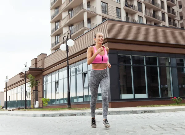 Konut kompleksi yakınlarında koşma pratiği yapan sağlıklı bir kadın.