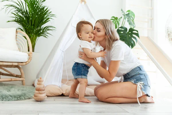 Anne sevgisi kavramı. Anne kucaklar ve küçük kızını yanağından öper. Odada çadırı kurar.