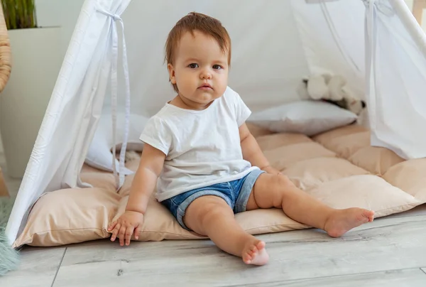 Little girl sitting in a wigwam at home