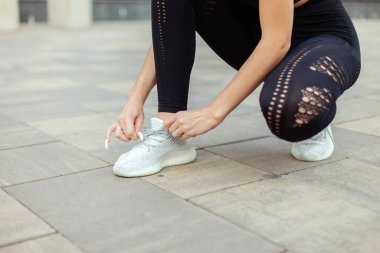 Dışarıda spor ayakkabısının bağcıklarını bağlayan güzel, zinde bir kadın.