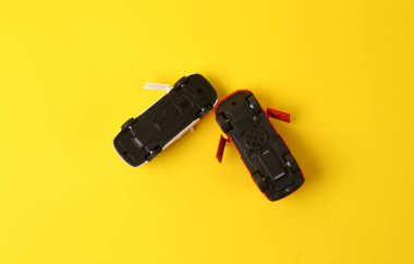 Sarı arka planda iki ters dönmüş oyuncak araba kazası, kaza, trafik kazası.