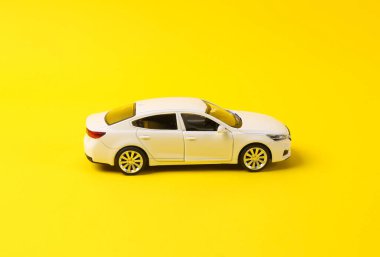 Sarı arka planda beyaz oyuncak arabanın mini modeli.