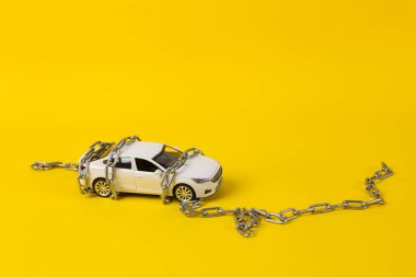 Oyuncak araba modeli sarı arka planda çelik bir zincir ile geri sarıldı. Ehliyet iptal kavramı